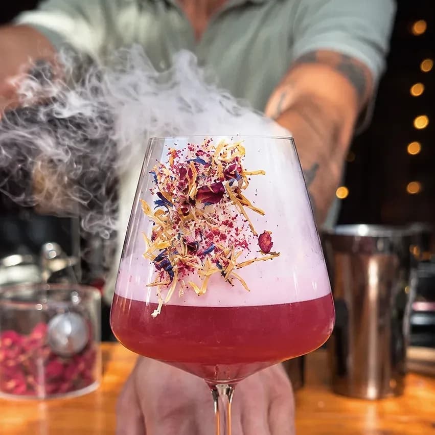 Une création sans alcool garnie d'une fumée aromatique, posée sur un dessous de verre en cuir.