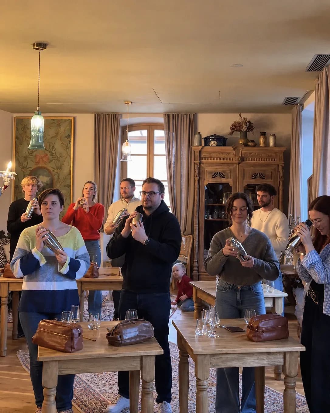 Un groupe d'ateliers lève son shaker à l'unisson, dans un salon chaleureux.